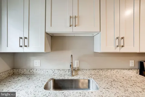 a kitchen with stainless steel appliances granite countertop white cabinets and a stove top oven