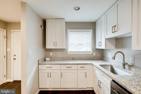 a kitchen with granite countertop white cabinets and white appliances