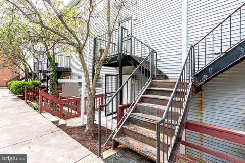 a view of a house with wooden deck stairs and a large tree