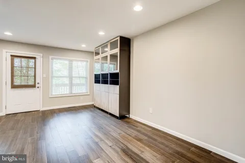 a view of an empty room with wooden floor and windows