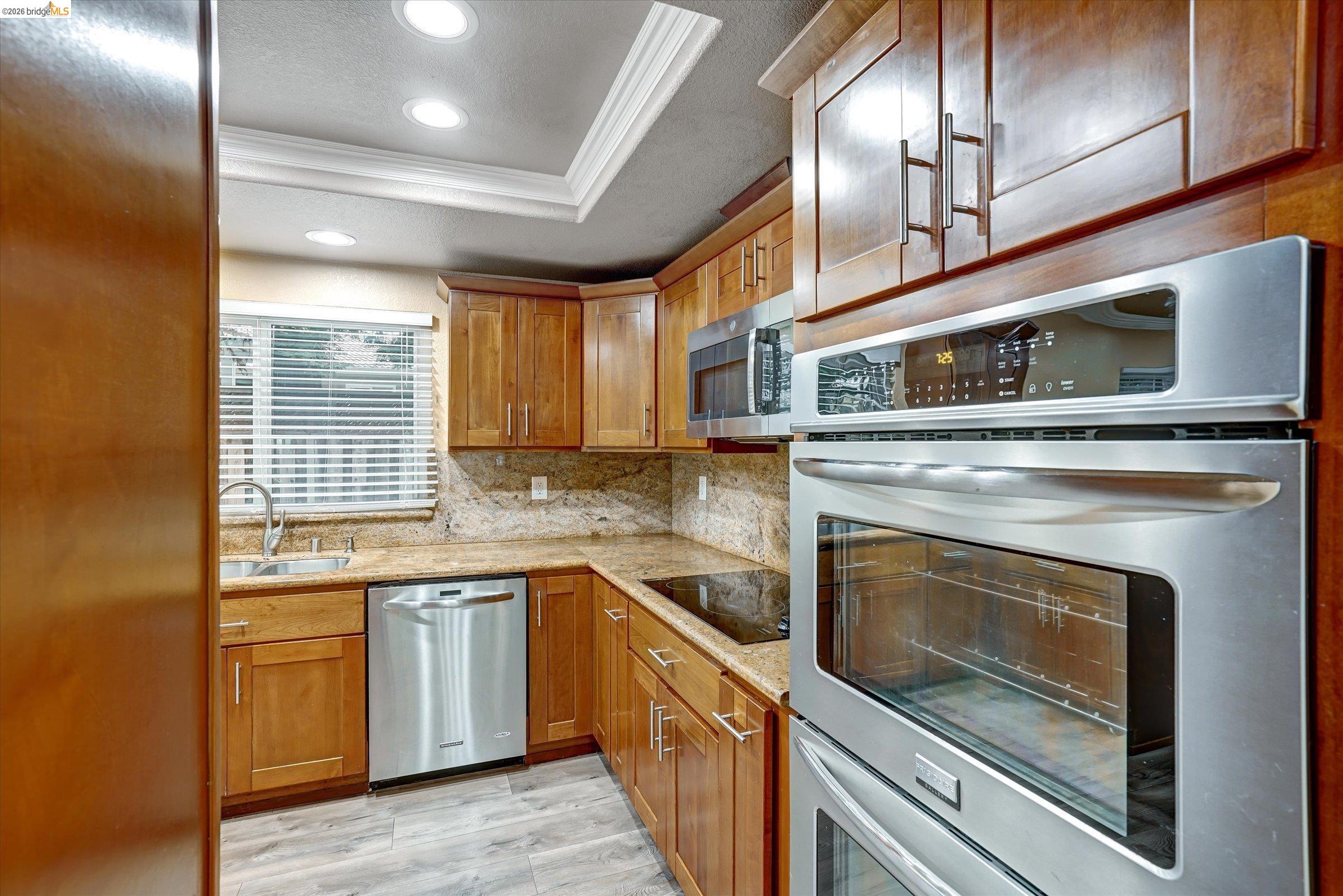 108 Castleton Court San Ramon, CA 94583 - Photo 10 of 41 Kitchen featuring ornamental molding, light wood finished floors, stainless steel appliances, wood finish cabinetry, and a textured ceiling