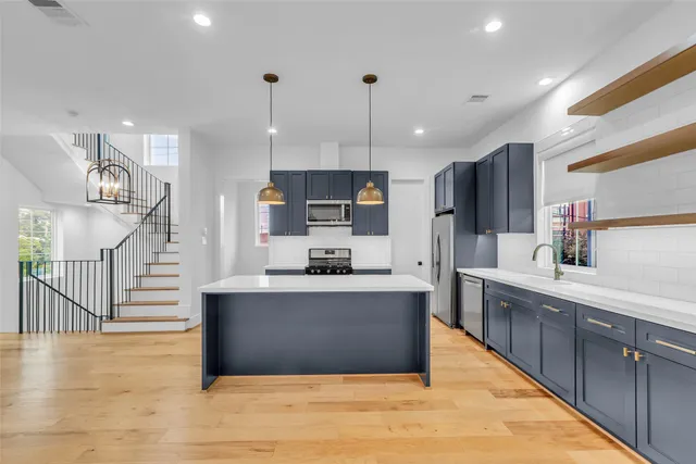 a large kitchen with stainless steel appliances kitchen island granite countertop a large kitchen island and a wooden floors