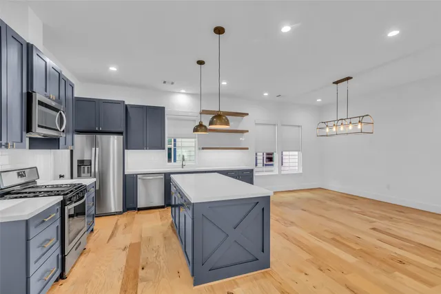 a kitchen with stainless steel appliances granite countertop a sink a stove and a refrigerator