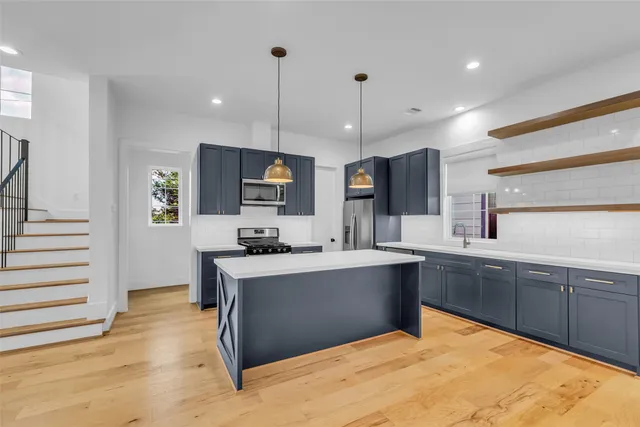 a large kitchen with stainless steel appliances kitchen island granite countertop a stove and a sink