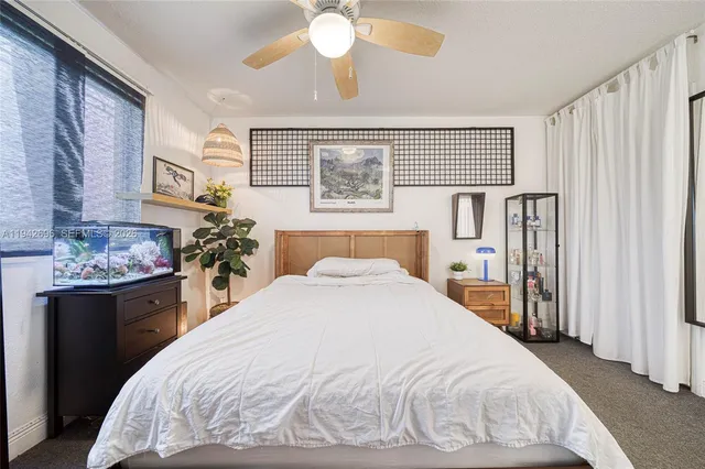 a large white bed in a bedroom next to a window and a chandelier