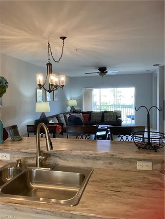 a kitchen with a sink a chandelier and living room view