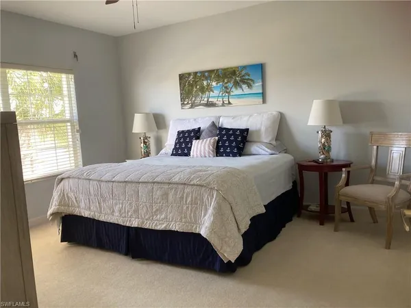 a spacious bedroom with a bed table chair and window