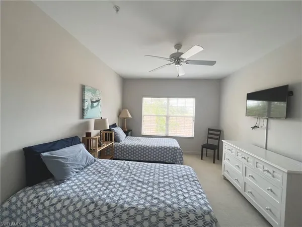 a bedroom with a large bed and a flat tv screen on dresser