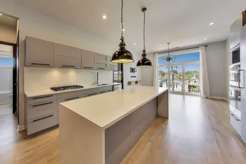 a large kitchen with kitchen island a stove a sink a center island and wooden floor