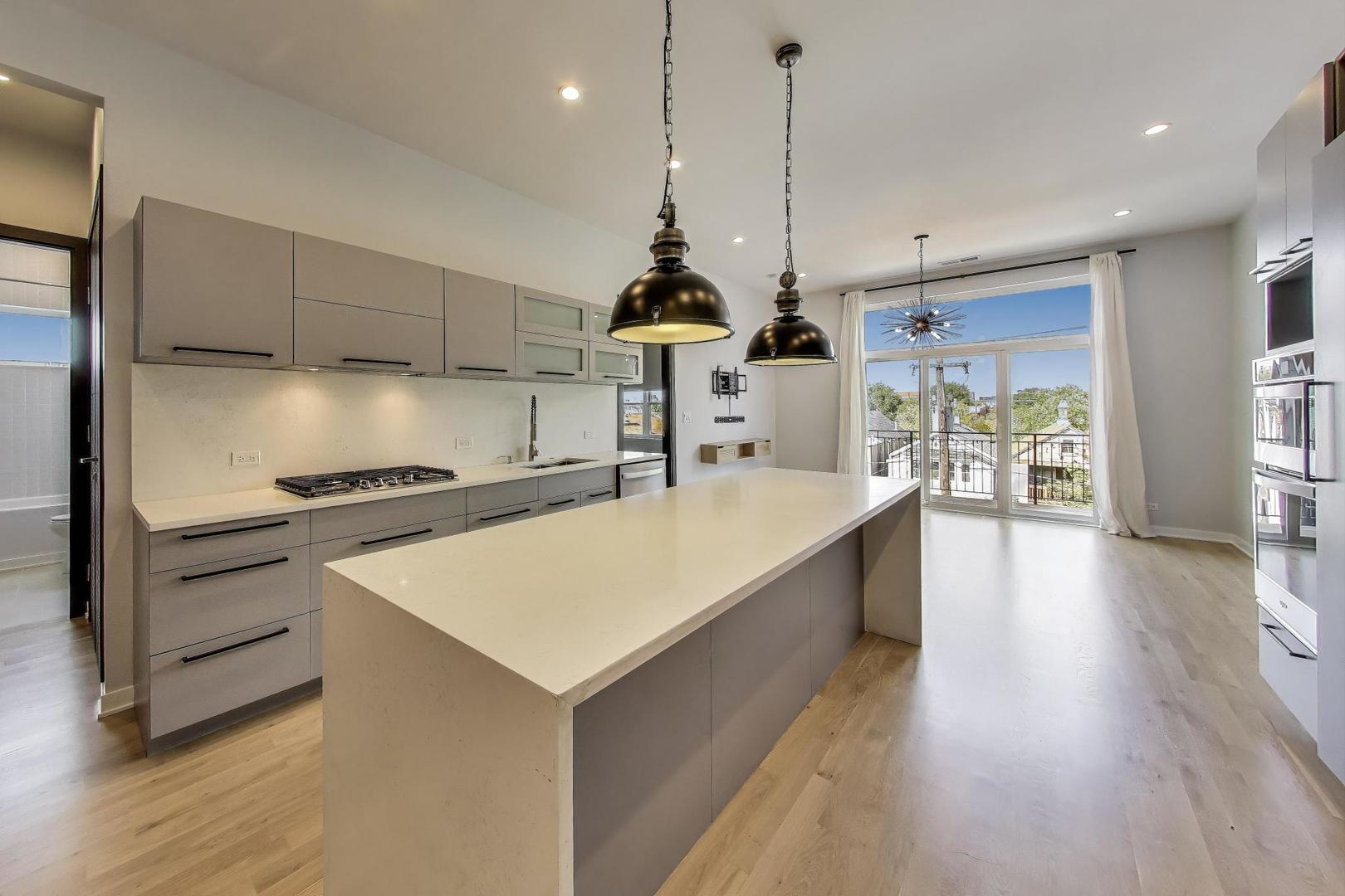 1708 West Cermak Road, Unit 3W Chicago, IL 60608 - Photo 7 of 26 a large kitchen with kitchen island a stove a sink a center island and wooden floor