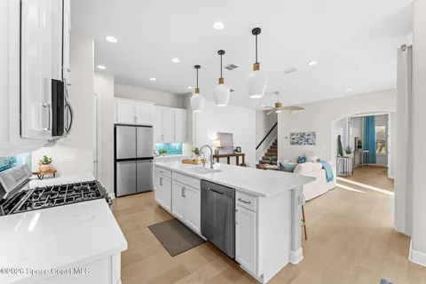 a large kitchen with kitchen island a refrigerator a stove a sink dishwasher a oven and a dining table with wooden floor