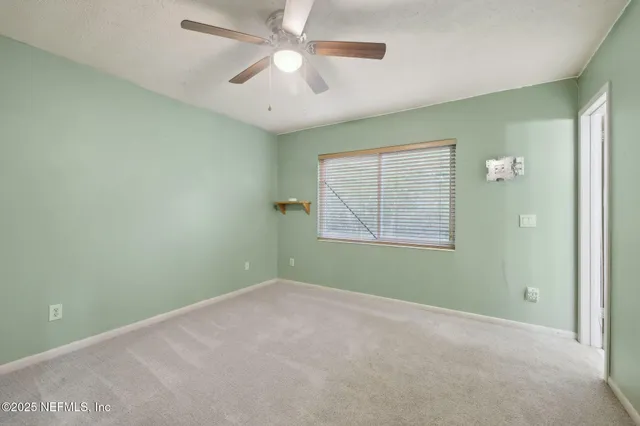 an empty room with windows and fan