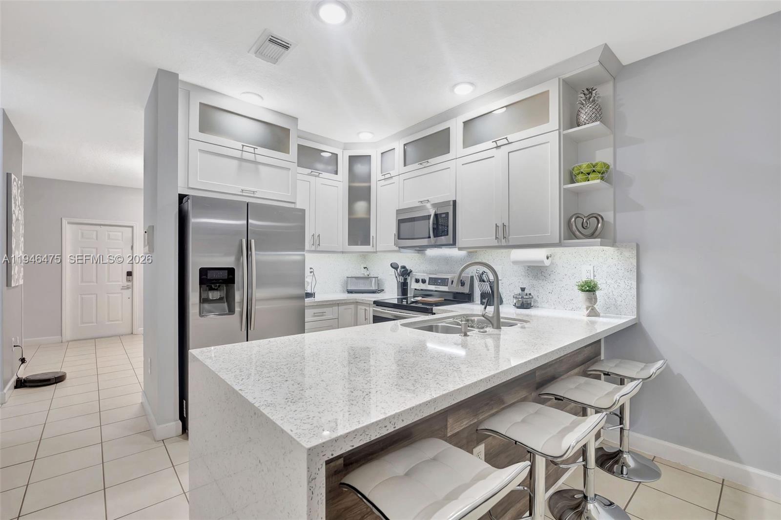 11227 Southwest 230th Terrace, Unit 11227 Miami, FL 33170 - Photo 13 of 37 a kitchen with stainless steel appliances granite countertop a sink a stove a refrigerator cabinets and chairs