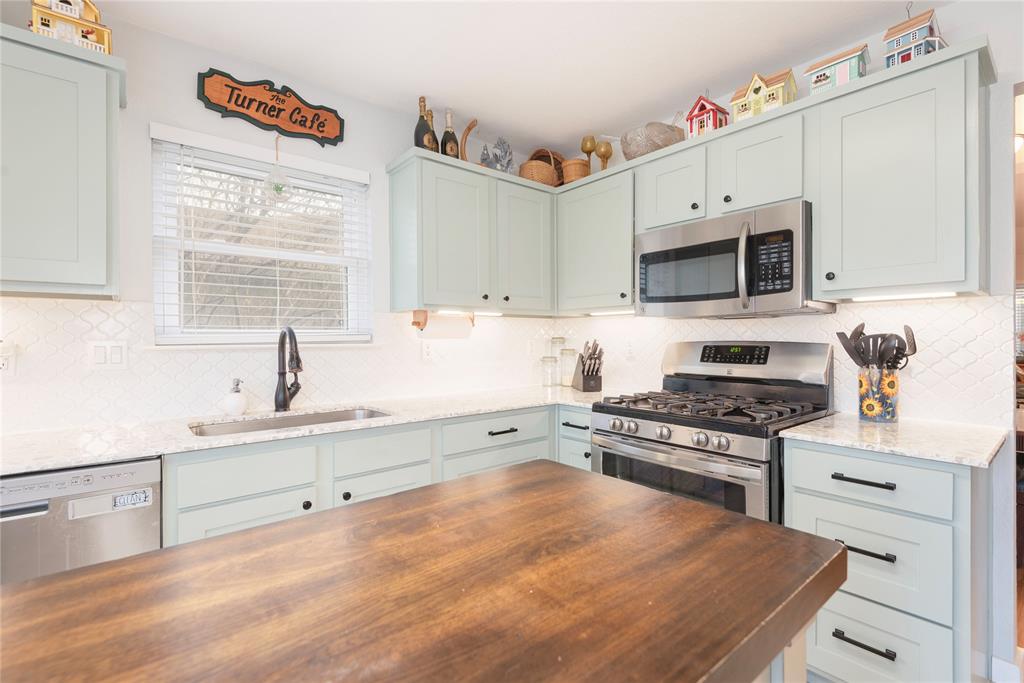 7613 Dockside Drive Rowlett, TX 75088 - Photo 37 of 40 a kitchen with stainless steel appliances a stove sink microwave and cabinets
