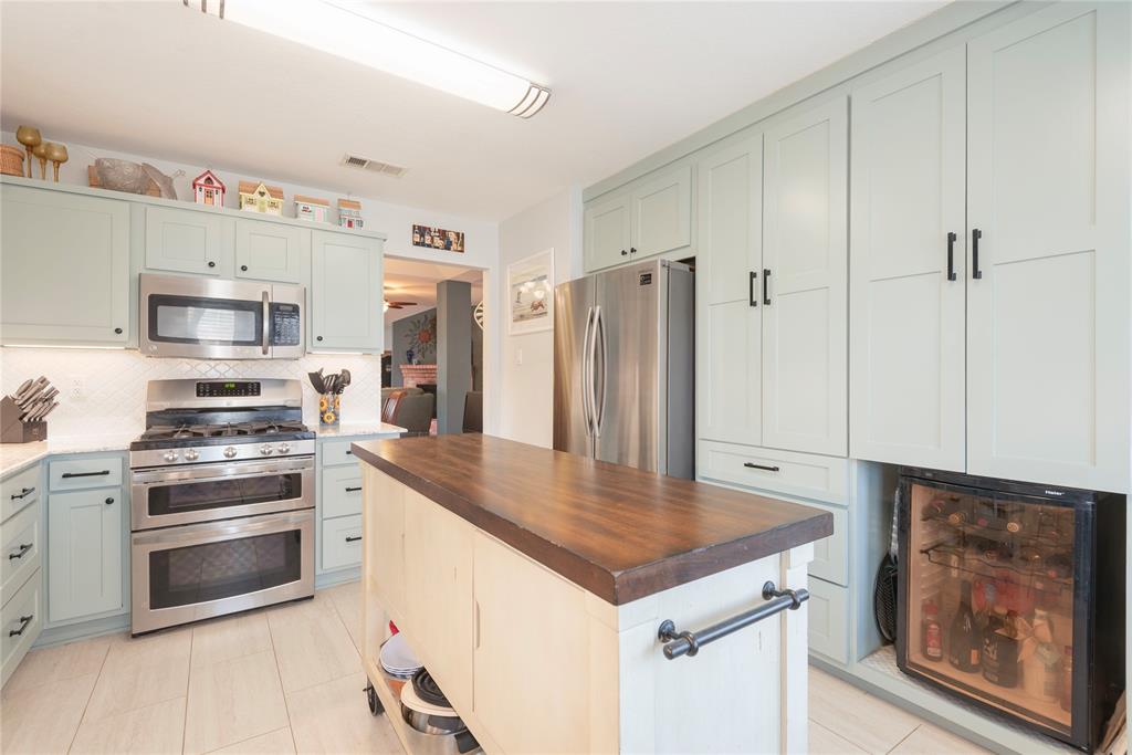 7613 Dockside Drive Rowlett, TX 75088 - Photo 9 of 40 a kitchen with stainless steel appliances a stove a refrigerator and a sink with wooden floor