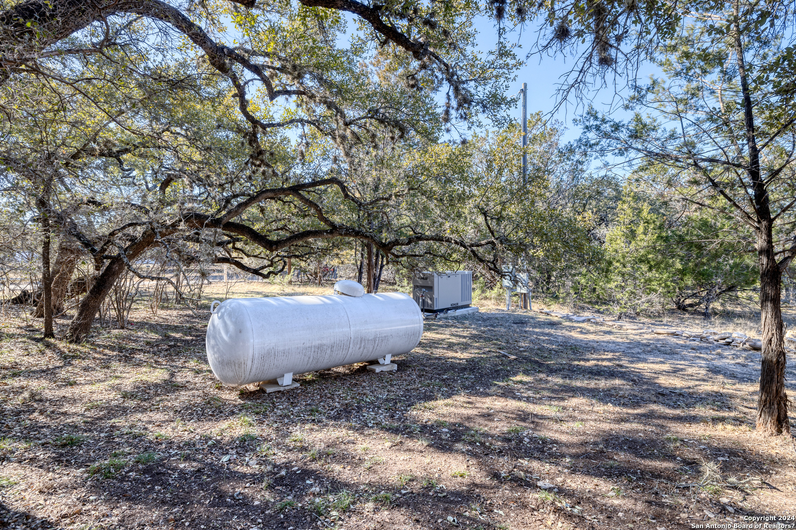 93 North Saddle Mountain Road Rio Frio, TX 78879 - Photo 10 of 50 a view of a backyard with large trees and wooden fence