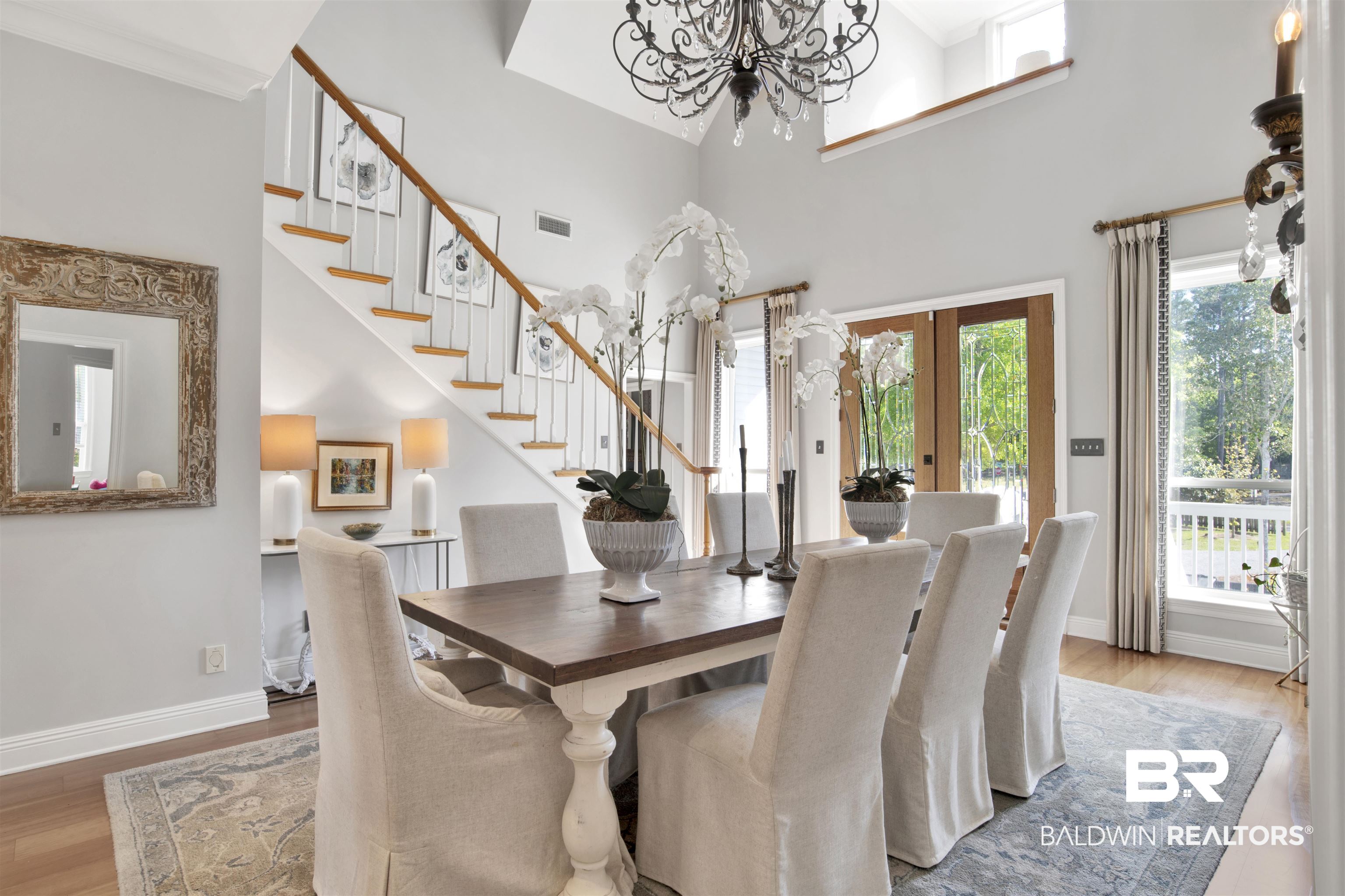 11463 Getchell Drive Theodore, AL 36582 - Photo 3 of 39 Dining room featuring a chandelier, wood-type flooring, a towering ceiling, and french doors