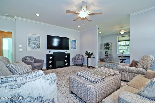 a living room with furniture a ceiling fan and a flat screen tv