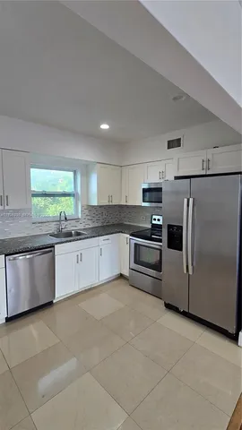 a large kitchen with granite countertop a stove a sink dishwasher and a refrigerator