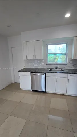 a large kitchen with granite countertop white cabinets and a sink