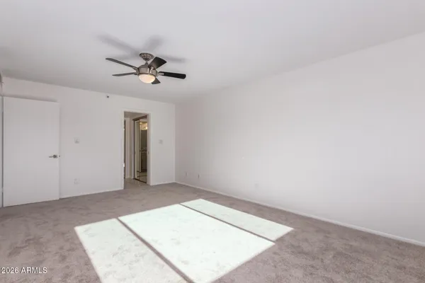 an empty room with a ceiling fan and carpet