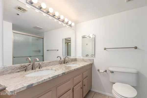 a bathroom with a granite countertop sink a toilet and a mirror