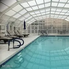 a view of a swimming pool with chairs in front of house