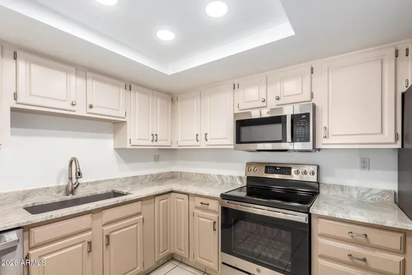 a kitchen with granite countertop white cabinets and stainless steel appliances