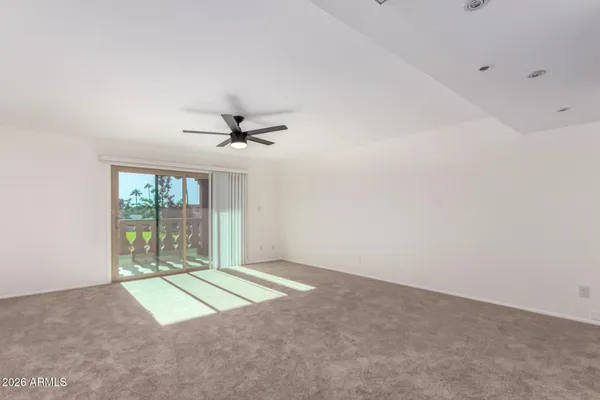 an empty room with windows and ceiling fan