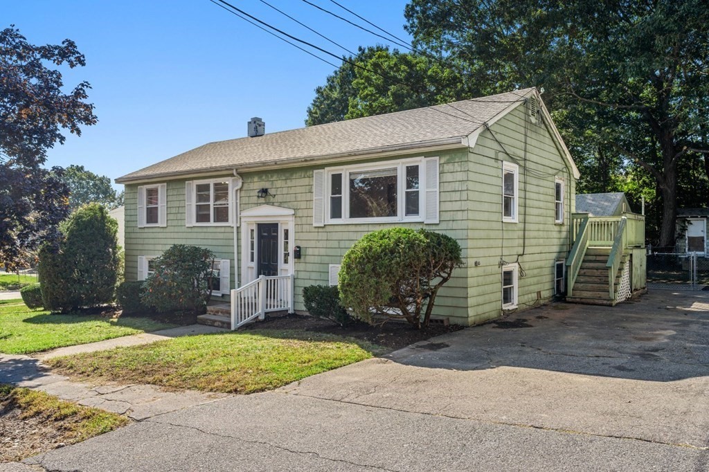 a view of a house with a yard and large tree
