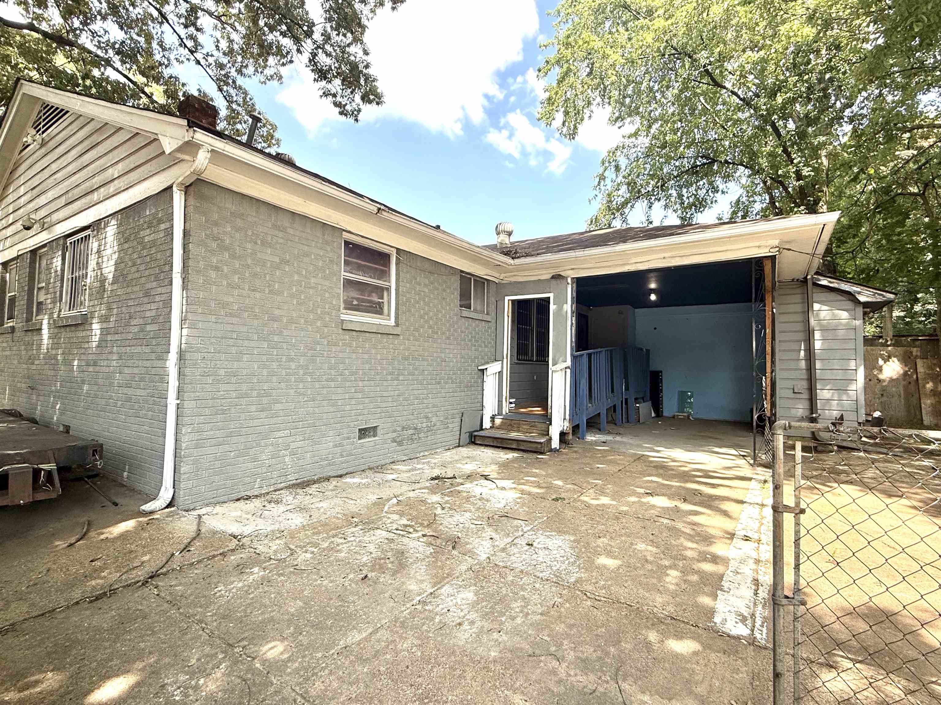 2930 Getwell Road Memphis, TN 38118 - Photo 22 of 25 Rear exterior featuring painted brick siding, a covered carport, and a chain-link fence