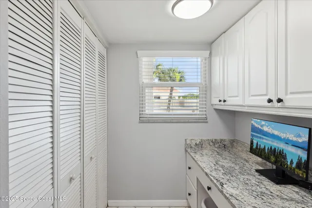 a kitchen with granite countertop white cabinets and window