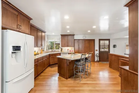 a kitchen with stainless steel appliances granite countertop a refrigerator a sink dishwasher a stove with wooden cabinets and wooden floor