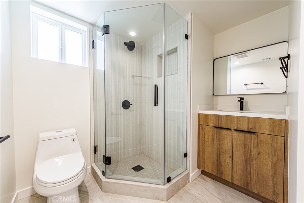1859 1/2 South Crenshaw Boulevard Los Angeles, CA 90019 - Photo 18 of 29 a bathroom with a toilet a sink and glass door