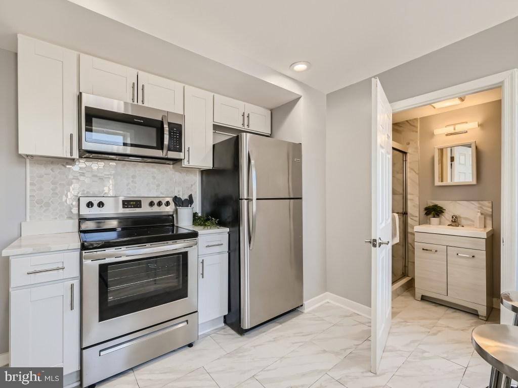 1402 Carroll Street Baltimore, MD 21230 - Photo 11 of 28 a kitchen with stainless steel appliances white cabinets a stove a microwave and a refrigerator