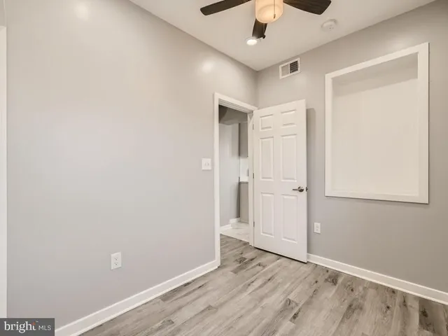 an empty room with a hardwood and ceiling fan