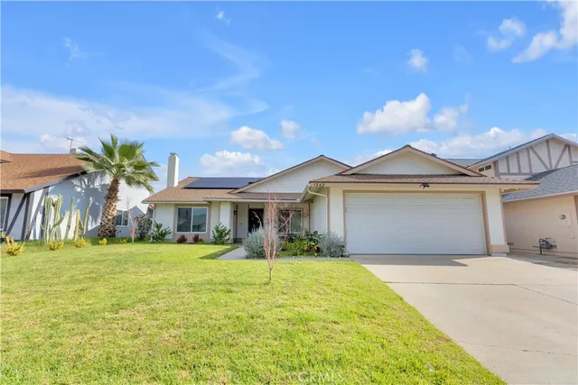 a front view of a house with a yard and palm trees