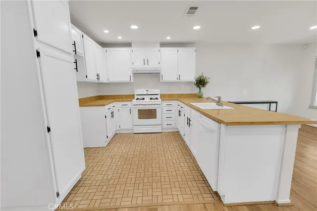 a kitchen with a sink a stove top oven and white cabinets