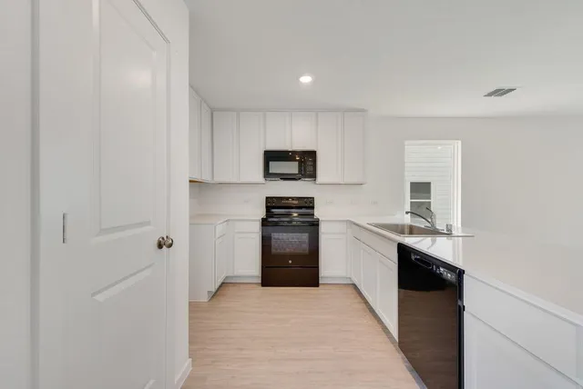 a kitchen with granite countertop white cabinets and stainless steel appliances