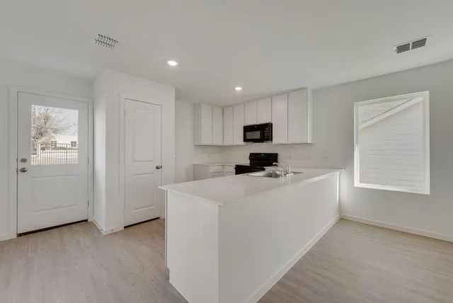 a view of kitchen with stainless steel appliances granite countertop white cabinets and window