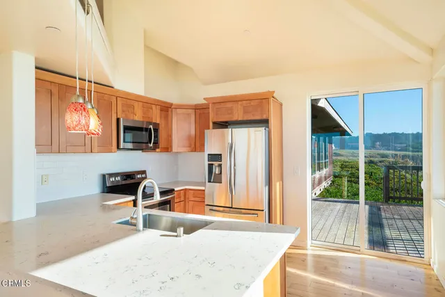 a kitchen with stainless steel appliances granite countertop a sink a stove and a wooden floors