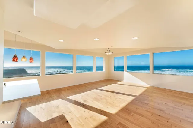 a view of an empty room with wooden floor and windows