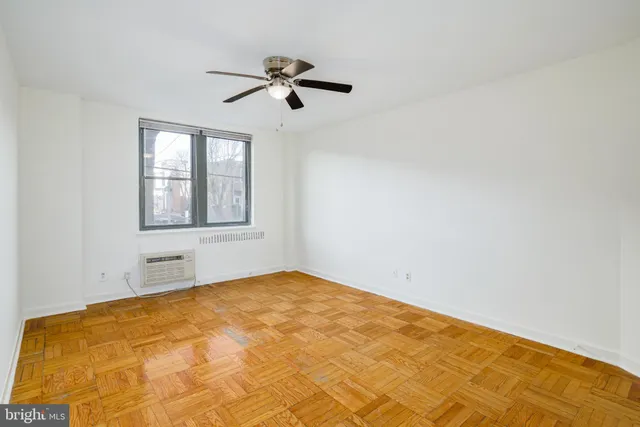 a view of empty room with wooden floor and fan