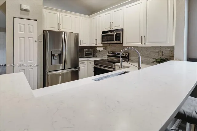 a kitchen with refrigerator a microwave a stove and cabinets