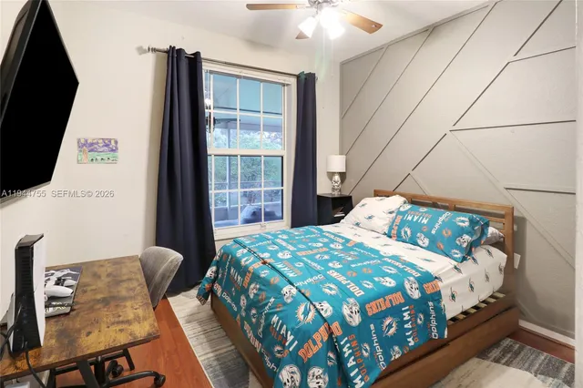 a bedroom with a bed a flat screen tv and next to a window