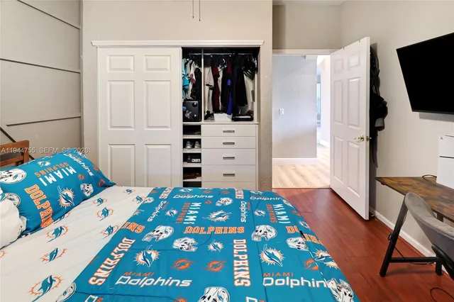 a bedroom with a bed and flat tv screen on the dresser