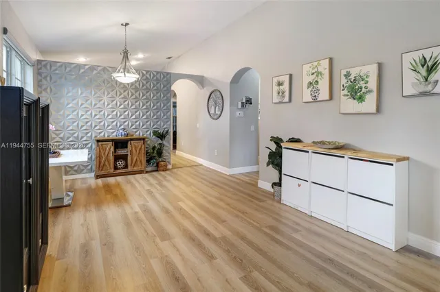 a view of empty room with kitchen view and wooden floor