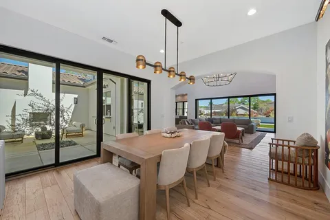 a dining room filled chandelier and wooden floor