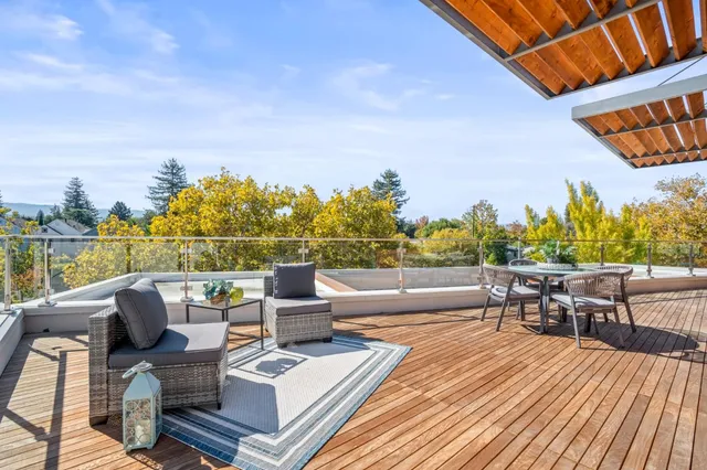 a view of roof deck with seating space and trees in the background