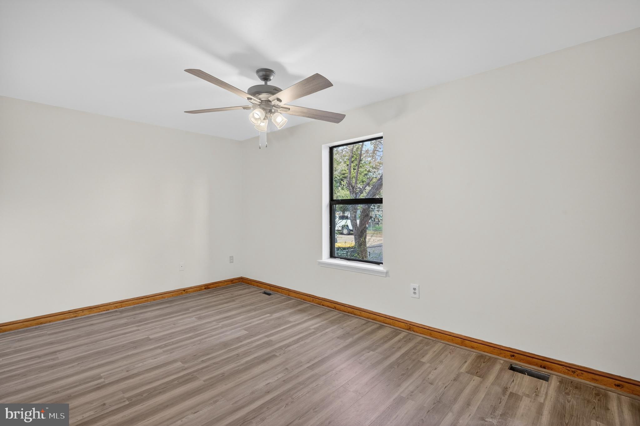 4037 1st Street Chesapeake Beach, MD 20732 - Photo 13 of 26 an empty room with wooden floor chandelier fan and windows